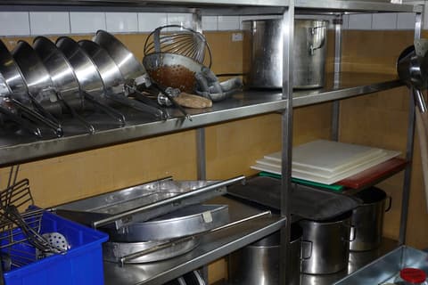 Étagères en inox d’une cuisine professionnelle avec casseroles et ustensiles