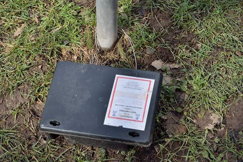 Poste d’appâtage sécurisé pour rongeurs posé au sol, avec étiquette d’avertissement